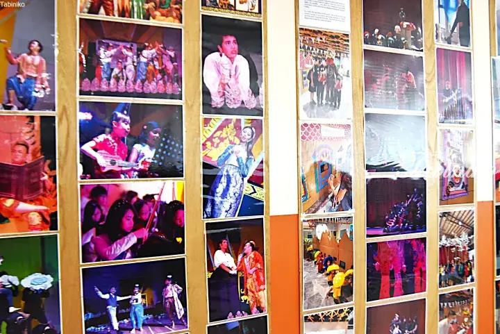 A display board showcasing vibrant photos of students performing traditional Malaysian dances and music.