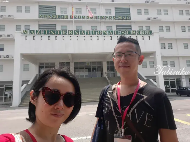Couple posing in front of Maz International School building in Malaysia.