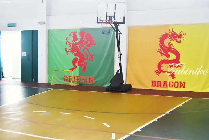 Indoor basketball court with green Griffin and yellow Dragon banners hanging on the wall.