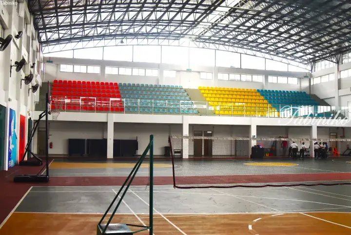 Indoor sports hall with colorful tiered seating and basketball court