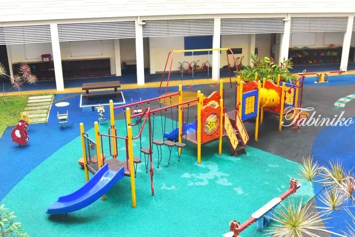 Colorful playground with slides and swings on soft rubber flooring at a modern Malaysia school or kindergarten.