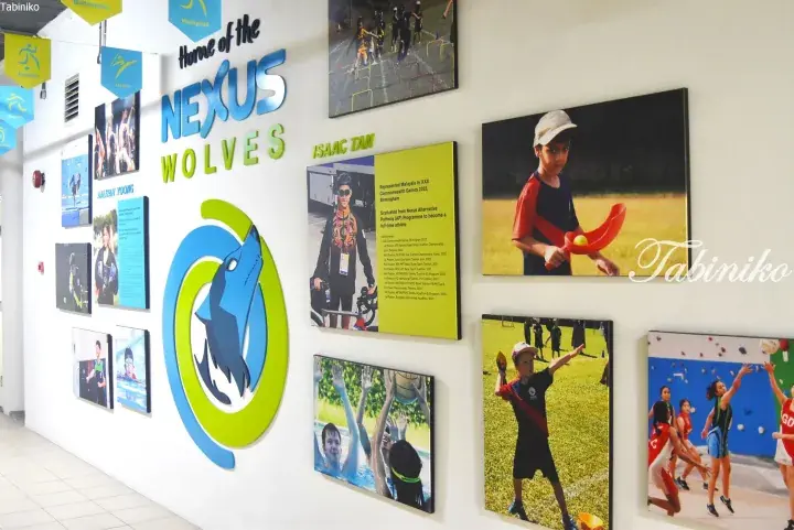 School hallway featuring the Nexus Wolves mascot logo and display panels showcasing student athletes like Isaac Tan.