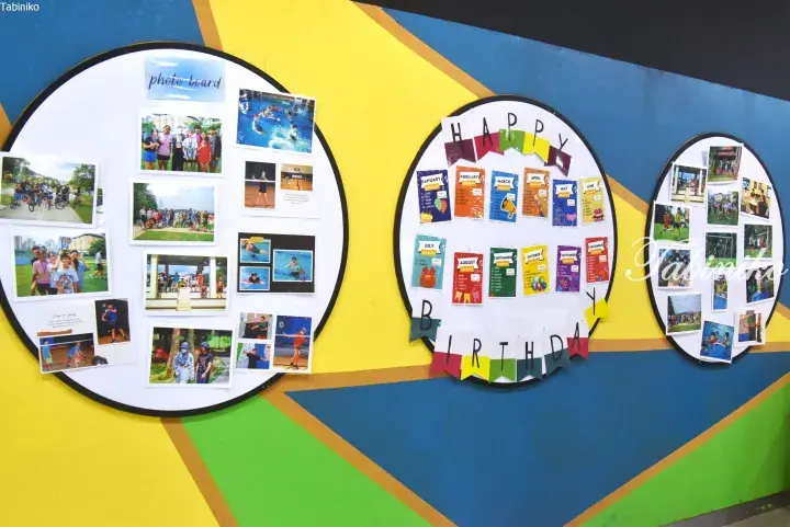 Colorful circular bulletin boards on a vibrant wall display student photos and a birthday calendar at a Malaysia school.