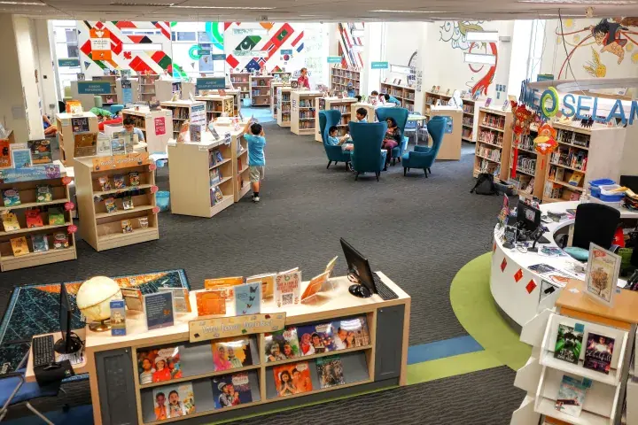 Bright children’s library section with colorful flags, bookshelves, and reading chairs in a Malaysian public library.