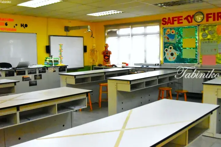 Empty science laboratory with student desks, whiteboards, and anatomical models in a school setting.