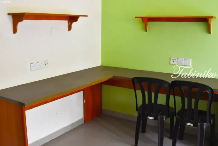 L-shaped study desk with shelves and power outlets in a room with green and white walls