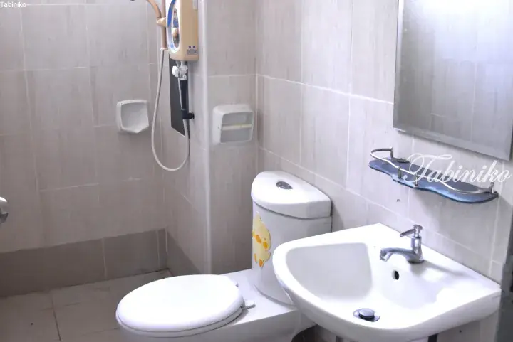 Clean bathroom with a white toilet, sink, mirror, and wall-mounted water heater in a tiled room.
