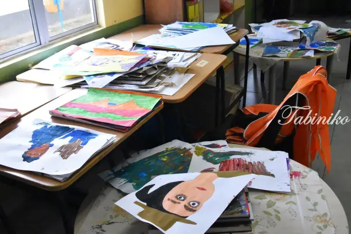 Colorful children’s artwork displayed on classroom tables near a window.