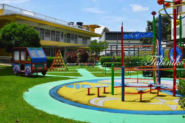 Colorful playground with a van-shaped swing and climbing structures at a Malaysia kindergarten.