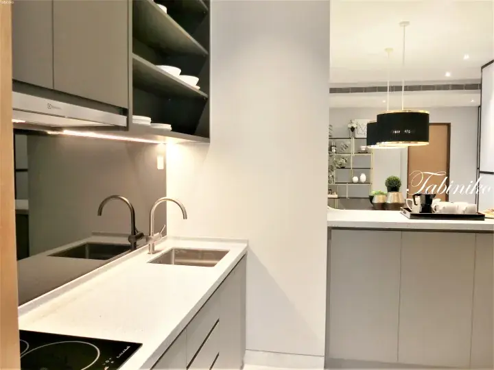 Modern kitchen with grey cabinets, white countertop, double sink, and pendant lights in a luxury apartment.