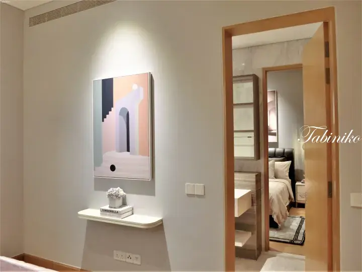 Modern hallway with abstract art, floating shelf, and view into a bedroom with marble accents.