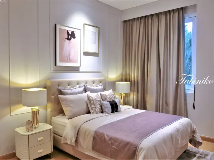 Elegant bedroom with a tufted headboard, beige curtains, and soft lighting in a modern Malaysian property.