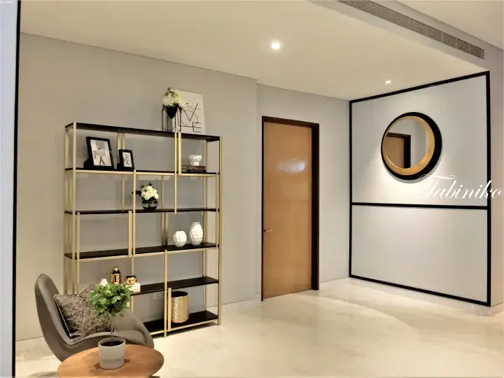 Modern interior with gold shelving, grey chair, and round mirror in a bright room