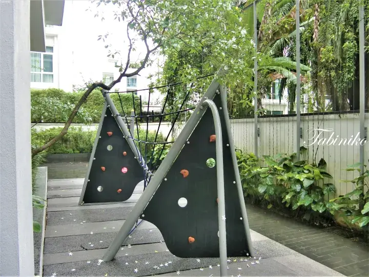 Modern triangular climbing wall with rope net in lush tropical garden at a Malaysia residential property.