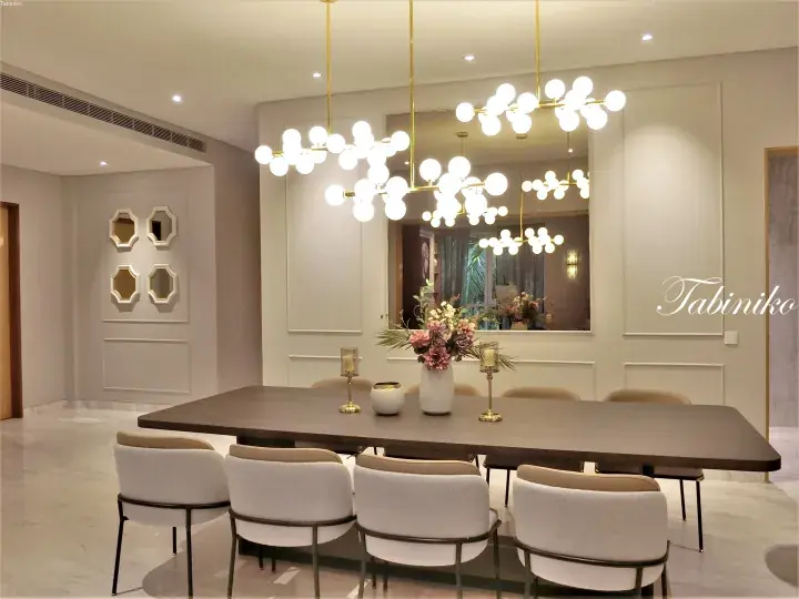 Modern dining room with a dark wooden table, beige upholstered chairs, and a unique multi-globe chandelier.