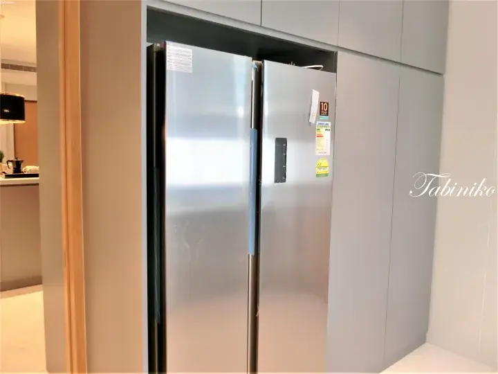 Stainless steel side-by-side refrigerator installed in a modern kitchen cabinet with energy label visible.