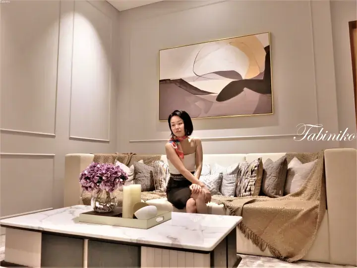 Woman sitting on a beige sofa in a modern luxury living room with abstract art and marble coffee table