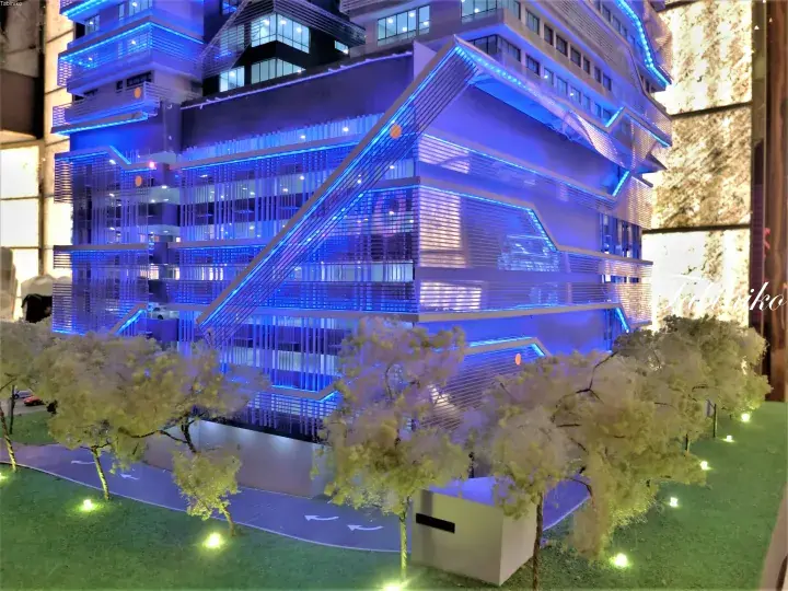 Architectural model of a modern blue-lit building with unique angular design and miniature trees