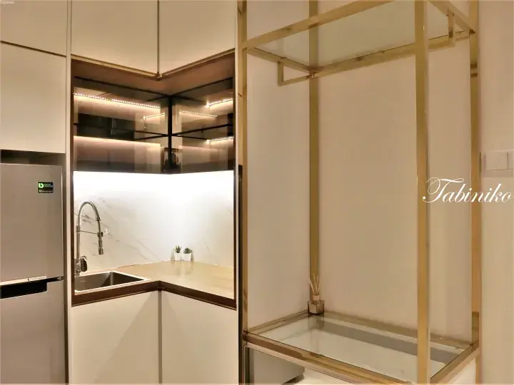 Modern kitchen with marble backsplash, wooden countertop, and gold-framed glass shelving unit