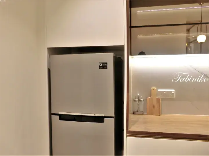 Modern kitchen featuring a built-in silver Samsung refrigerator with digital inverter technology, complemented by a marble backsplash and wooden countertop.