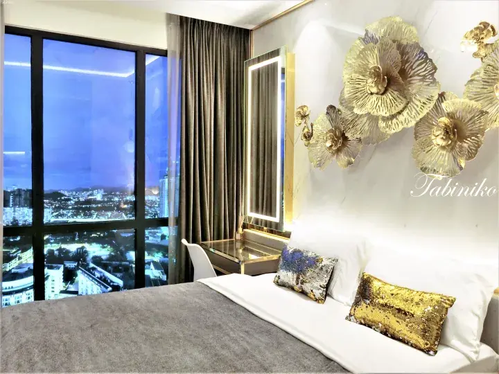 Modern bedroom with gold floral wall art and city night view from the window.