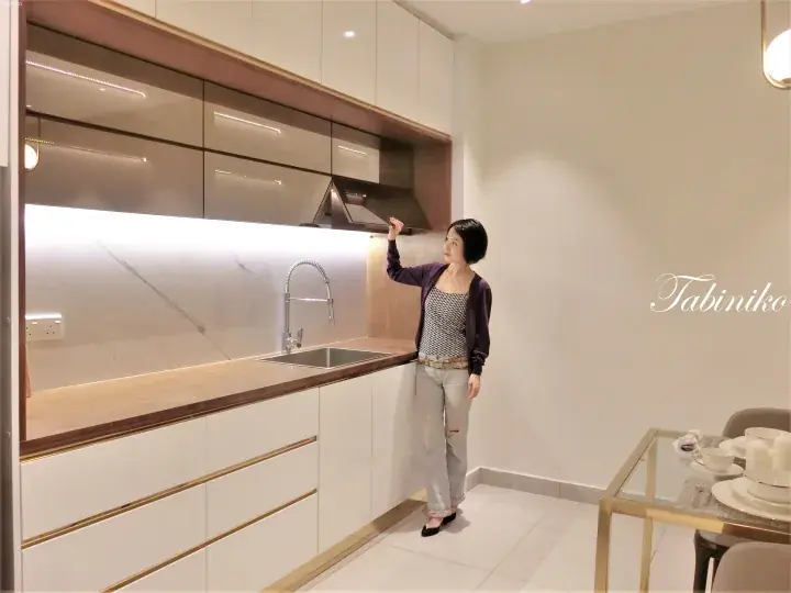 Woman in modern kitchen with marble backsplash and sleek cabinetry, showcasing property interior design.