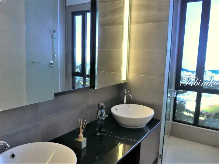 Modern bathroom with black marble countertop, white vessel sinks, and large window overlooking city view.