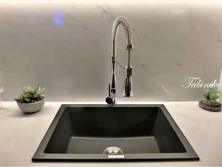 Modern black kitchen sink with chrome pull-down faucet on white marble countertop