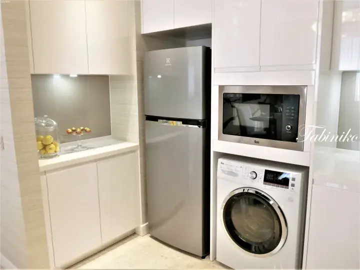 Modern kitchen interior featuring a silver Electrolux refrigerator, a Teka microwave, and a washing machine integrated into white cabinetry.