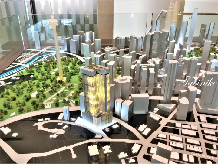 Architectural model of Kuala Lumpur showing the illuminated Ceylon Pavilion tower, KL Tower, and surrounding cityscape.