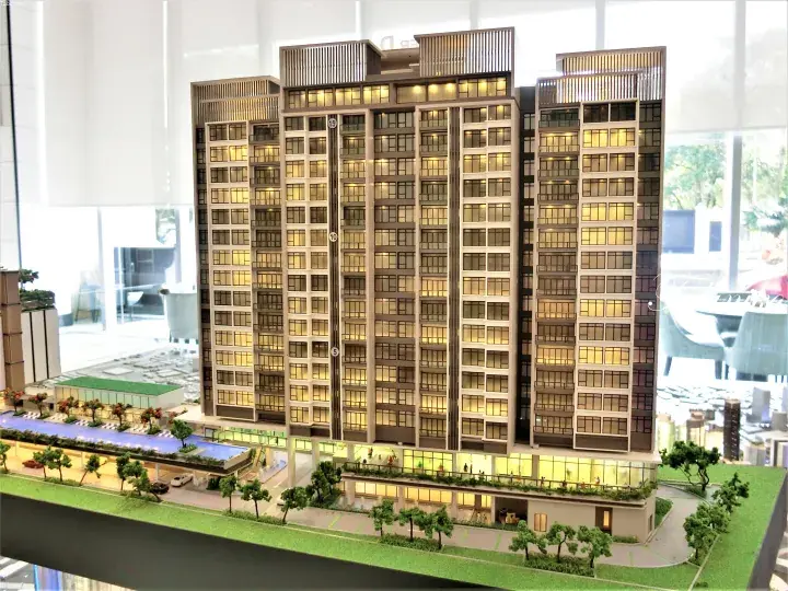 Architectural model of a modern high-rise condominium with illuminated windows, rooftop amenities, and a ground-level swimming pool.