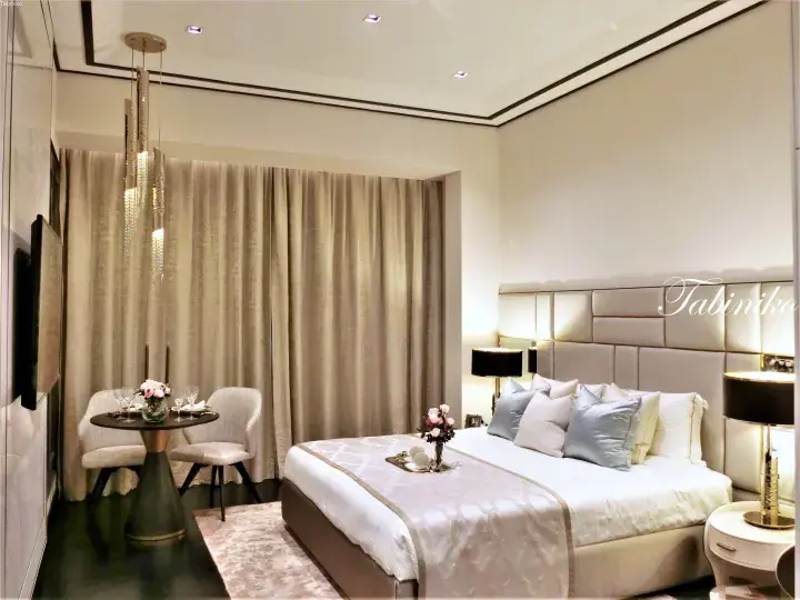 Luxury hotel bedroom with king bed, plush headboard, and elegant dining area in Kuala Lumpur
