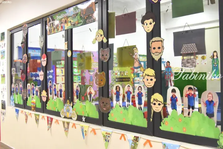 Classroom window decorated with traditional fairy tale characters and children’s photos for a storytelling theme.