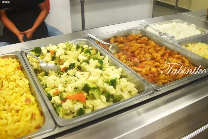 Buffet trays of macaroni, mixed vegetables, sweet and sour chicken, rice, and fried rice.