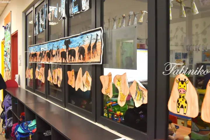 Colorful giraffe and safari animal artwork displayed on a classroom window.