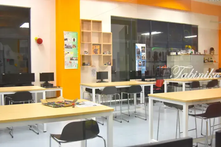 Bright modern co-working space with wooden tables, chairs, and computers in a Malaysia hub.