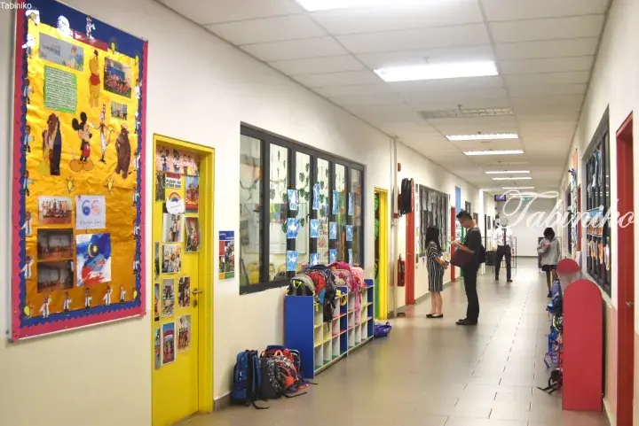 Colorful school hallway with student artwork, backpacks, and parents waiting outside classrooms.