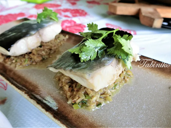 Grilled fish fillet served on a bed of savory minced filling, garnished with fresh cilantro on a rustic ceramic plate.