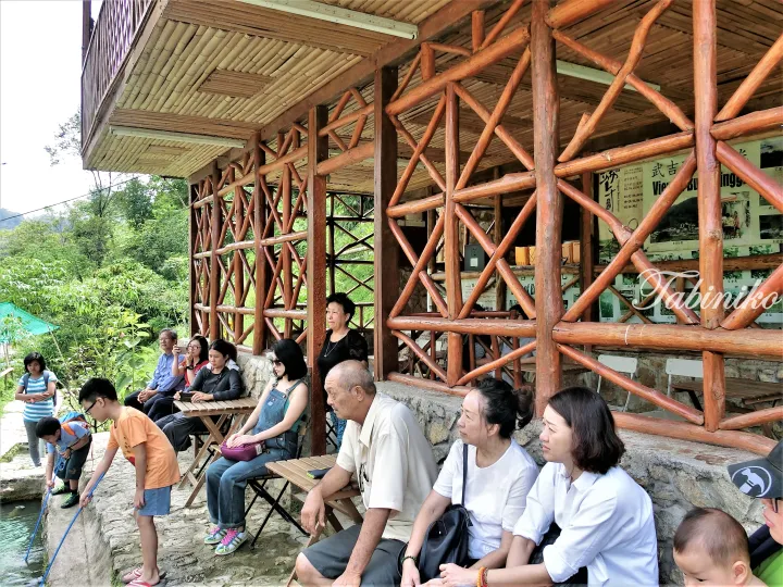 Tourists relax at a wooden pavilion in a lush Malaysian nature reserve.