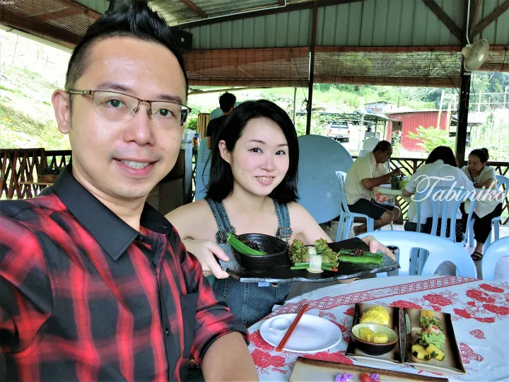 Couple enjoying a meal at an open-air restaurant in Malaysia, showcasing local dishes and a relaxed tropical dining atmosphere.