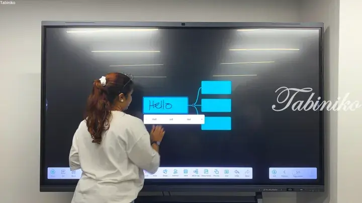 Woman using a large interactive digital whiteboard to create a mind map with the word ‘Hello’ in a modern office setting.