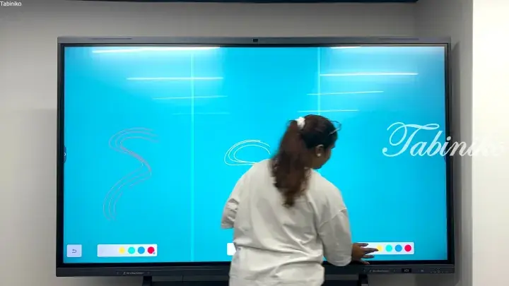 Woman interacting with a large digital whiteboard displaying blue graphics and the Tabiniko logo.