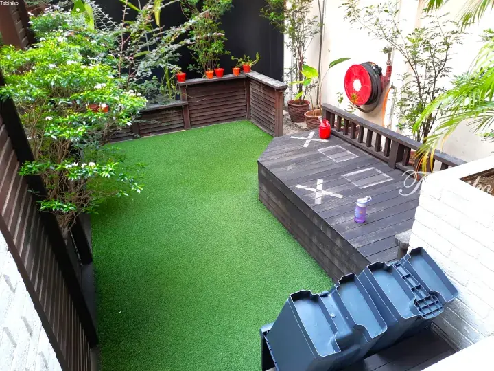 Private garden with artificial turf, wooden deck, and potted plants in a Malaysian property.