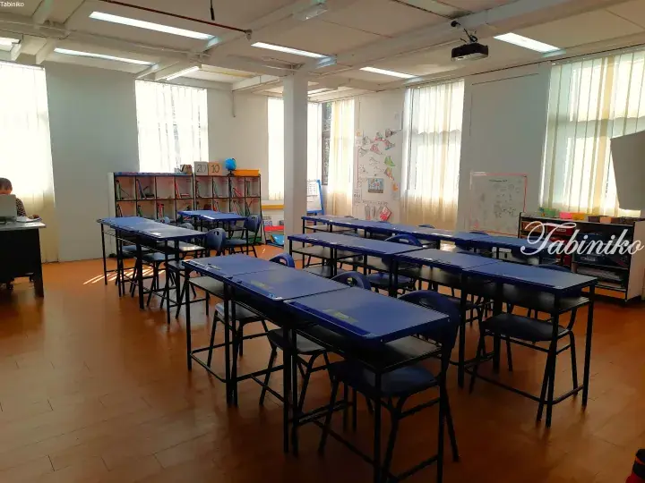 Bright classroom with blue desks and chairs, bookshelves, and a world map in a Malaysia learning center.