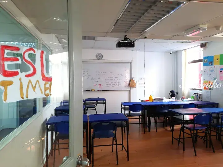 Bright ESL classroom with blue desks, whiteboard, and projector in a Malaysia learning center.