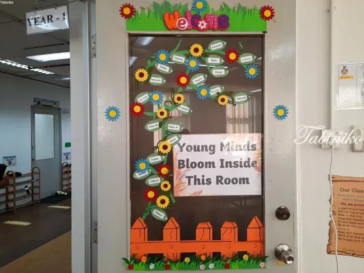 Year 1 classroom door decorated with a flower theme, student names, and “Young Minds Bloom Inside This Room” sign.
