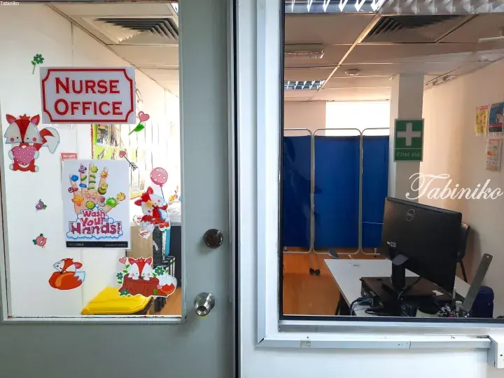 View into a school nurse office with a “Wash Your Hands” poster and a first aid station.