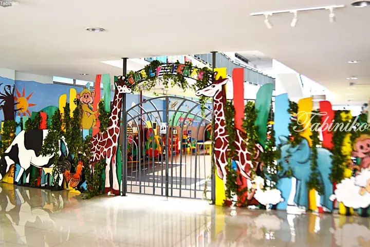 Colorful entrance to a children’s play area featuring large giraffe cutouts and animal decorations.
