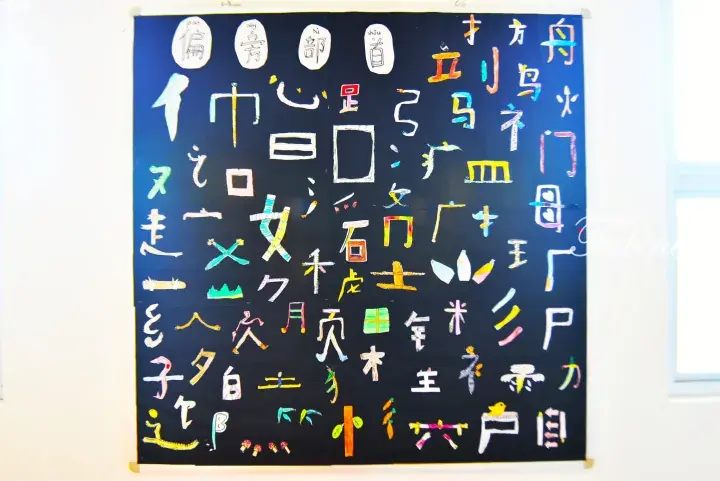 Colorful hand-drawn Chinese radicals and characters displayed on a dark blue classroom bulletin board.
