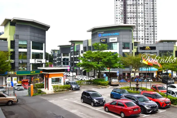 Modern commercial buildings with parking lot and cars in front of high-rise apartments in Malaysia.